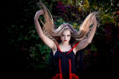 A woman in the woods holding up her long hair.