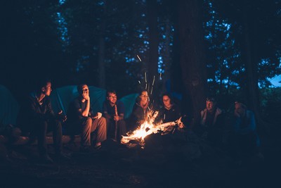 A group of people sat around a bonfire at night.